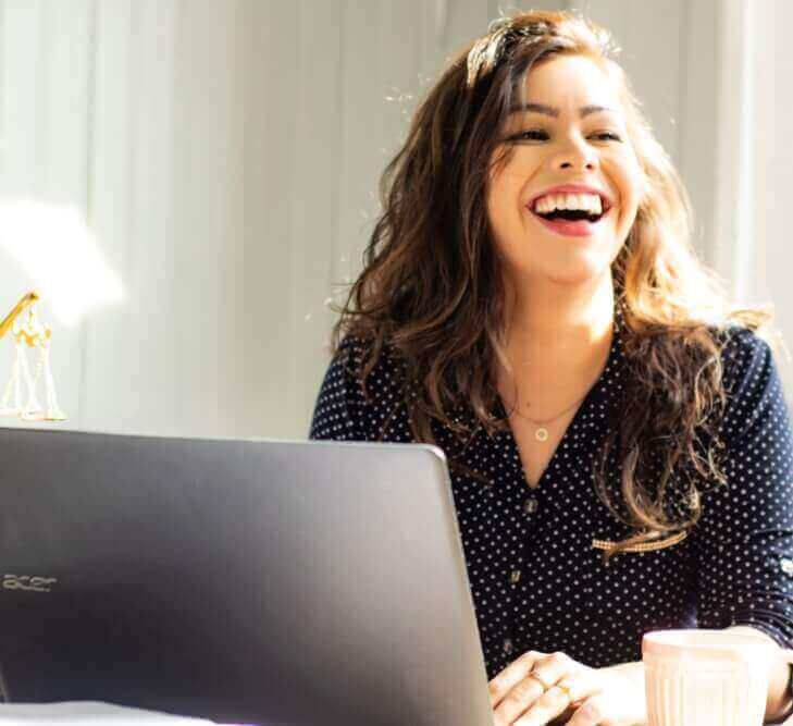 Mulher sorrindo enquanto digita no seu notebook